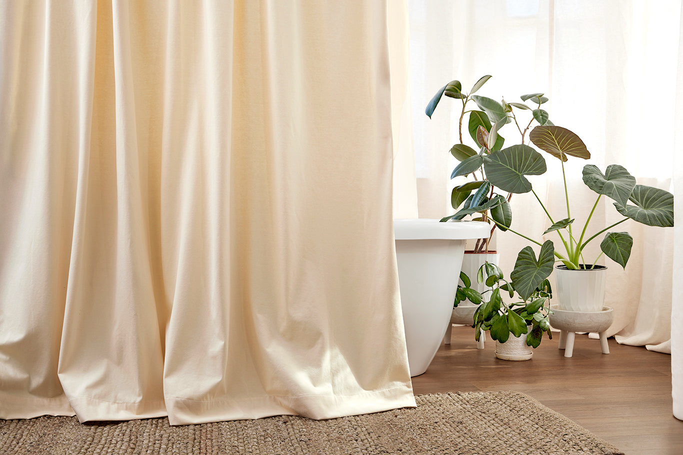 The Loving Liner draped in front of a bathtub, textural area rug and green plants with natural light.